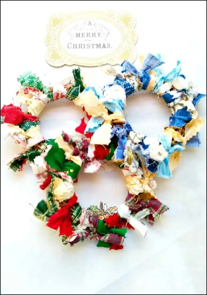 Three vibrant fabric wreaths crafted from colorful scraps—blue, green, and red—each adorned with a